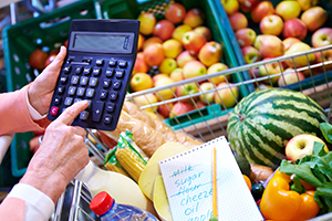 Individual holding calculator at grocery store in produce section.