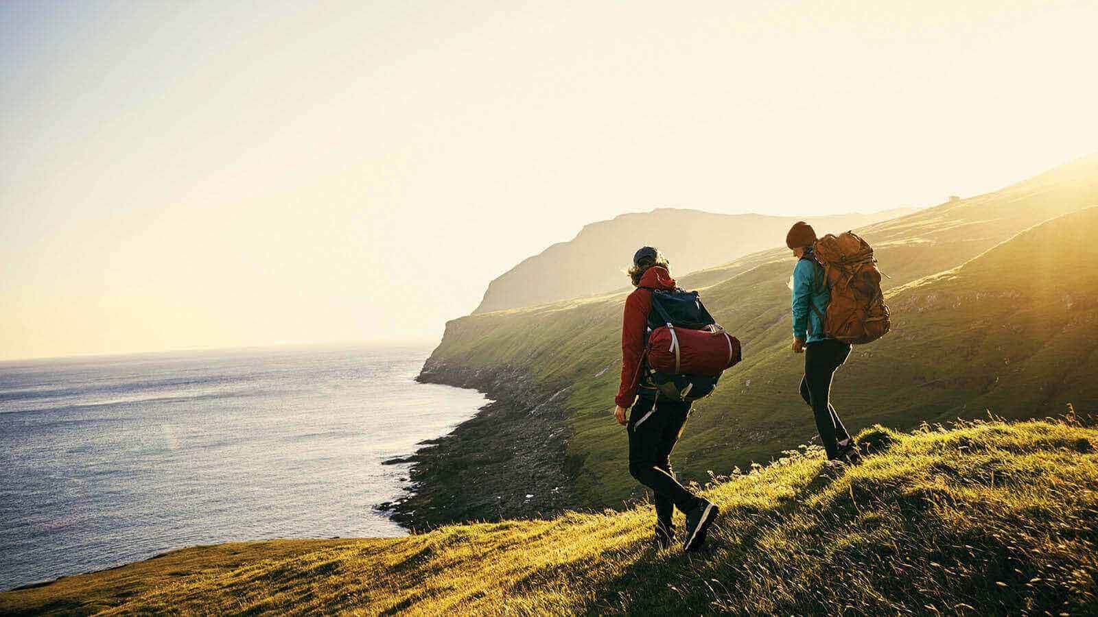 A young couple hiking on a hilly coastline.