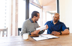A son sits next to his father, proud to be a second-generation financial professional working alongside his father in their family’s financial practice.