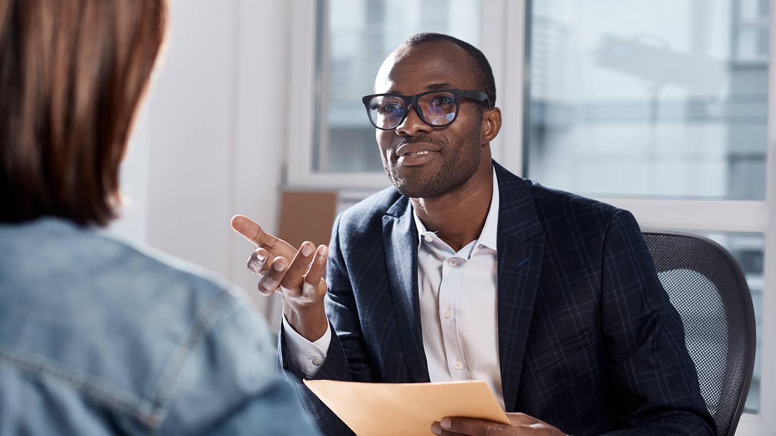 Man sitting at a table, holding papers and explaining himself.