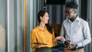 Man in glasses having conversation with woman in yellow shirt.