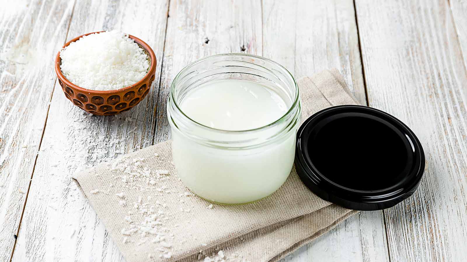 Coconut oil cream on bowl on white wooden table