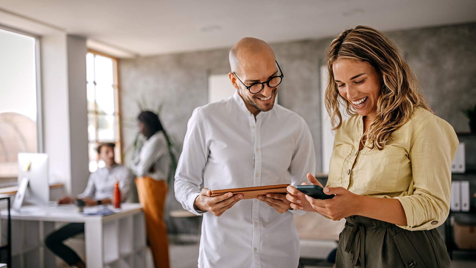 Businessman and businesswoman smiling looking at phone