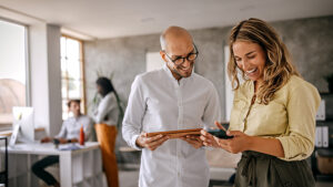 Businessman and businesswoman smiling looking at phone