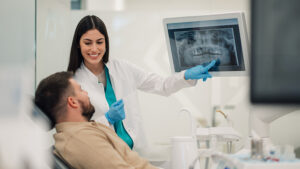 Dentist showing teeth x-ray to patient in modern clinic