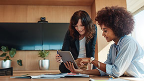 A female financial professional discusses a plan with her young, female client about how to save money and pay off debt.