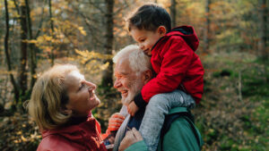 Grandparents enjoy a hike in the forest with their young grandson.