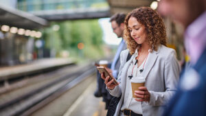 Smiling female looking at cell phone while waiting for subway.