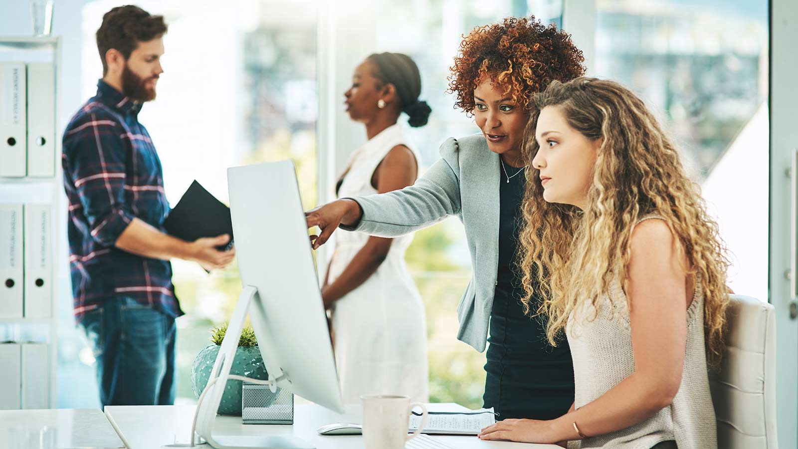 Employees in a work setting looking at a monitor.