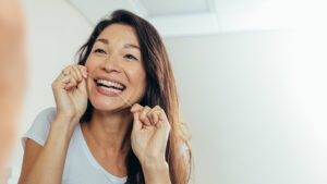 Reflection of woman using dental floss.