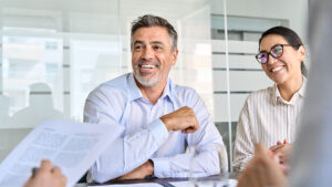 An independent financial professional smiles and laughs with his team during a meeting.