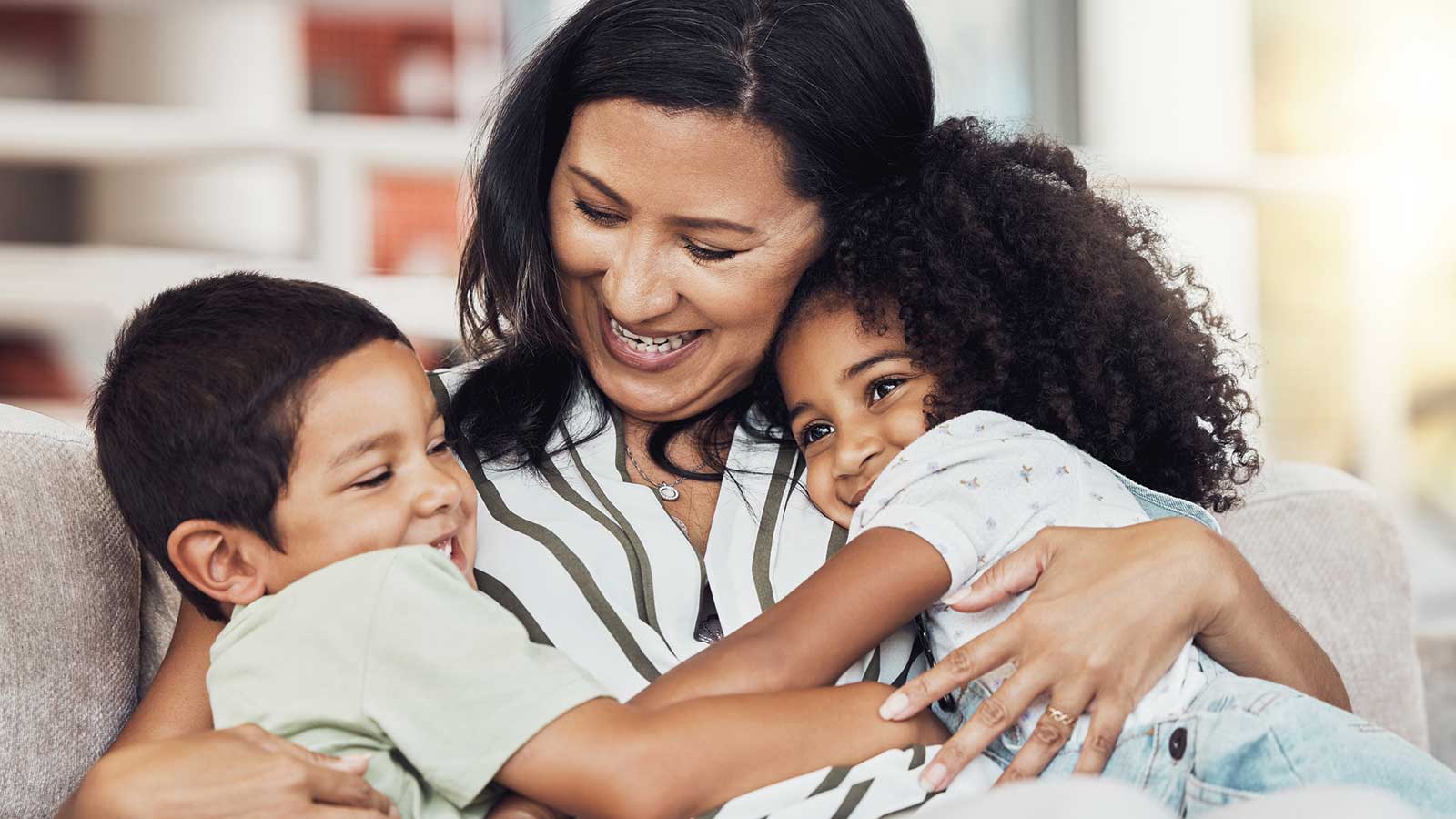 Mom hugging small children on couch