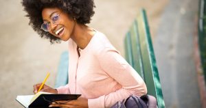 Female smiling while studying from a book.