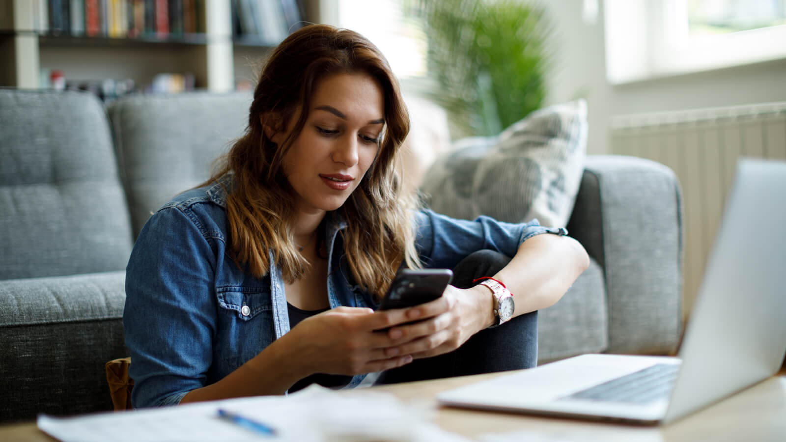 A young woman researches IRAs on her phone to learn the best options to meet her financial goals.